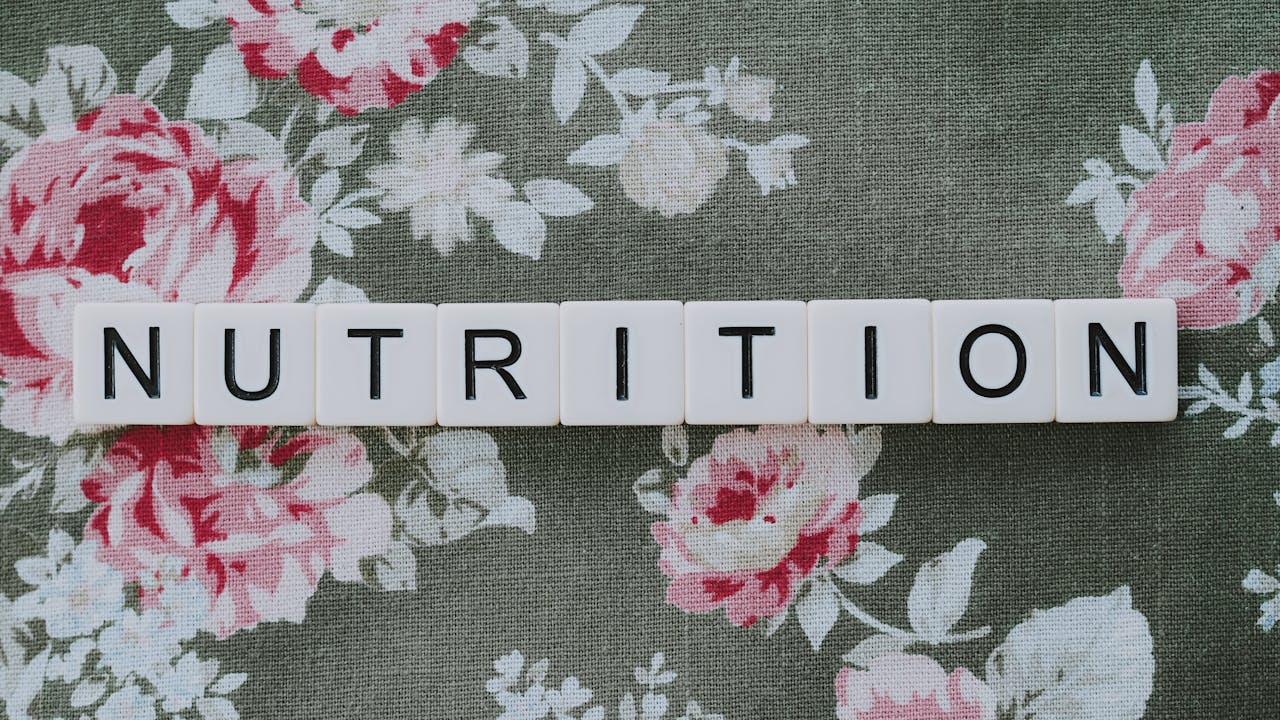 The word 'Nutrition' spelled with letter tiles on a floral background, evoking health concepts.